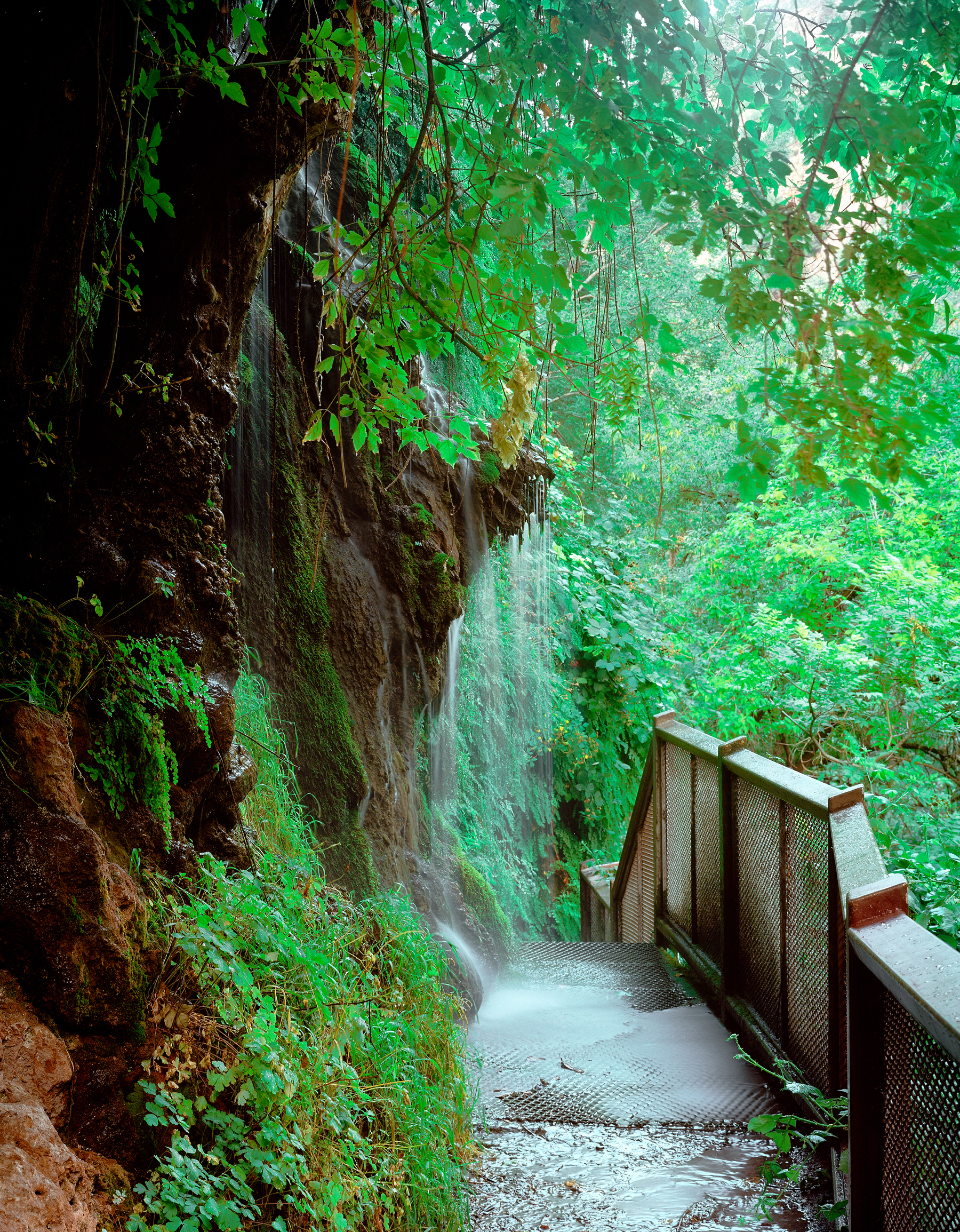 Waterfall cascading over travertine onto the trail at Tonto Natural Bridge.